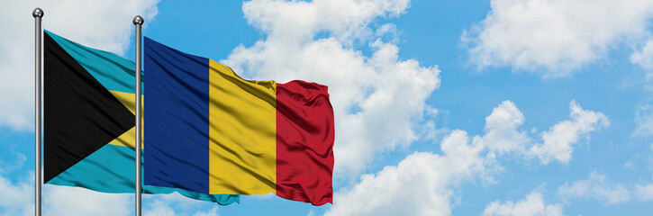 Bahamas and Romania flag waving in the wind against white cloudy blue sky together. Diplomacy concept, international relations.