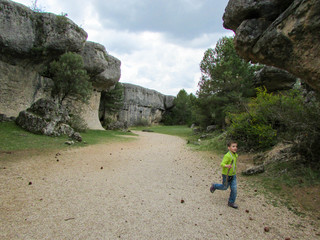 little curious tourist boy runs on the walkway surrounded by scenic and beautiful rocks of Ciudad Encantada (Enchanced city) geological site and national park in Spain