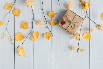 Woman packing gift in a box of kraft paper on white retro wood boards. leaves, birch branches. Thanksgiving. Autumn, fall concept. Flat lay, top view.