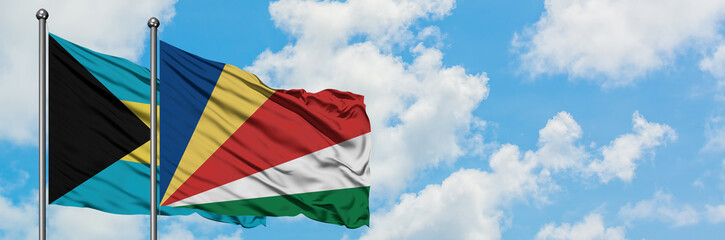 Bahamas and Seychelles flag waving in the wind against white cloudy blue sky together. Diplomacy concept, international relations.