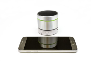 cellphone and silver bluetooth speaker isolated on white background