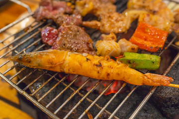 Assorted meat and seafood on flaming barbecue charcoal stove 