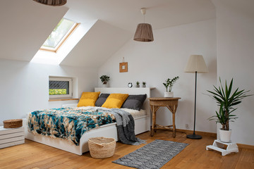 Modern bedroom interior in the bright attic.  Double bed with stylish pillows and furry bedspread. 