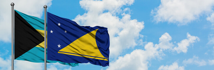 Bahamas and Tokelau flag waving in the wind against white cloudy blue sky together. Diplomacy concept, international relations.