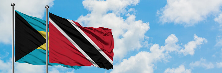 Bahamas and Trinidad And Tobago flag waving in the wind against white cloudy blue sky together. Diplomacy concept, international relations.