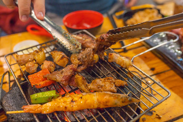 Closeup photo of human using tongs while grilling barbecue meat