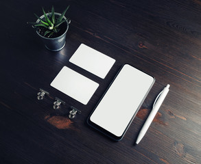 Smartphone, business cards, plant and pen on wooden background. Stationery mock up.