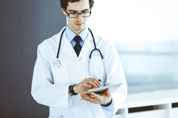 Doctor man using tablet computer for network research or virtual disease treatment. Perfect medical service in clinic. Modern medicine, medic data and healthcare concepts