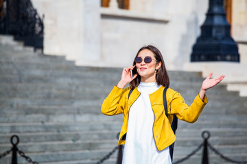 Fototapeta premium Asian woman walking and using a smart phone in the street in a sunny summer day. Businesswoman talking on her cellphone
