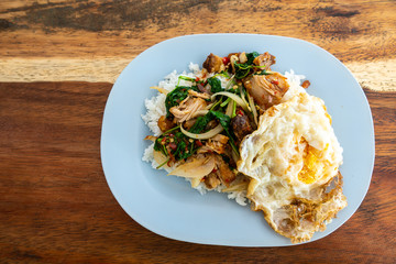 Rice and stir-fried crispy pork and basil with Fried egg background.