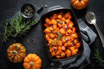Oven baked pumpkin slices with rosemary and seeds, healthy vegetarian food, top view - obrazy, fototapety, plakaty