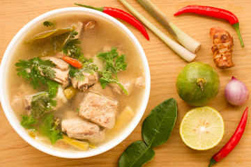 Hot and spicy soup with Cha Muang ribs In a white cup on a wooden table.
