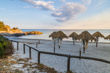 View of the empty beach with parasols and sea after sunset  in Villasimius, Sardinia (Sardegna) island, Italy. Holidays, the best beaches in Sardinia.