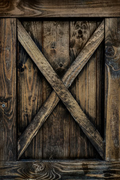 Detail of old wooden door with weathered planks, cross, knots and rings.