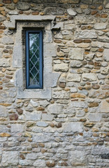 Small medieval leaded window seen on the side of an old medieval castle.