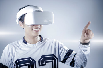The young man wearing virtual reality goggles at the studio isolated on grey