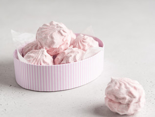 Pink marshmallows zephyr in stripped white and pink cartoon oval box on white background