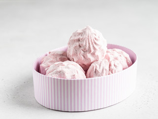 Pink marshmallows zephyr in stripped white and pink cartoon oval box on white background