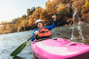Active senior man paddling kayak. Gray hair man enjoy river kayaking.
