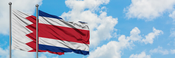 Bahrain and Costa Rica flag waving in the wind against white cloudy blue sky together. Diplomacy concept, international relations.