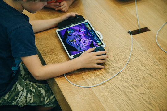 Berlin, August 29, 2018: A Child Plays An Electronic Game On An Apple Game Console Or On An IPad With A Special Joystick That Turns Into A Console.