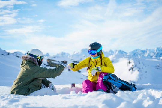 Image of two sportsmen doing handshake sitting on snow resort.