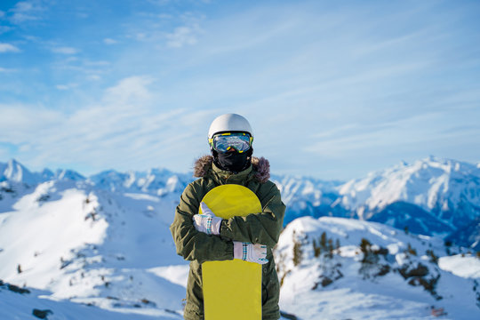 Photo of man in helmet with snowboard standing on snow resort .