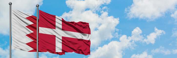 Bahrain and Denmark flag waving in the wind against white cloudy blue sky together. Diplomacy concept, international relations.