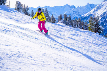 Photo of sportswoman in helmet snowboarding at winter resort.