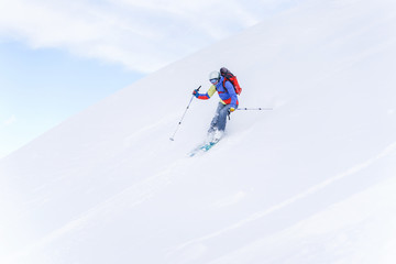 Naklejka na ściany i meble Side photo of sportsman with backpack skiing