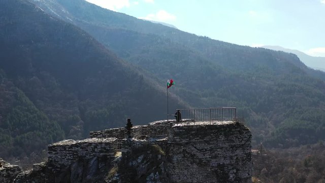 Aerial view of Bulgarian flag flying atop a castle in the mountains