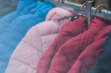Closeup of colorful winter jackets on hangers in fashion store showroom