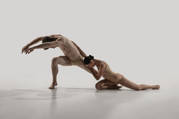 The group of modern ballet dancers. Contemporary art ballet. Young flexible athletic men and women in ballet tights. Studio shot isolated on white background. Negative space.