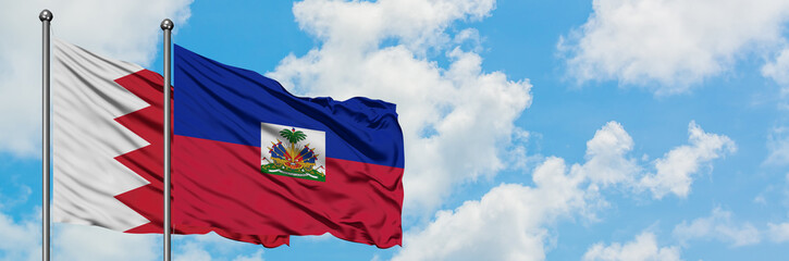 Naklejka premium Bahrain and Haiti flag waving in the wind against white cloudy blue sky together. Diplomacy concept, international relations.