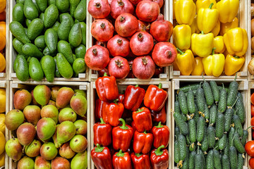 A counter with different vegetables in drawers is beautifully and evenly laid out from above. Carrots Potatoes cucumbers, bell peppers, onions, tomatoes.