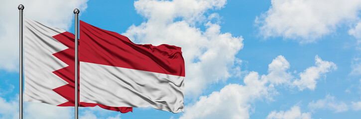 Bahrain and Indonesia flag waving in the wind against white cloudy blue sky together. Diplomacy concept, international relations.