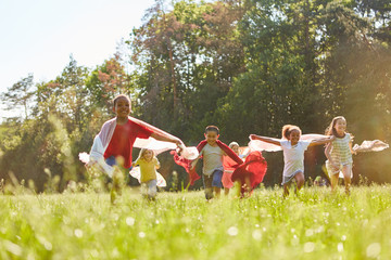 Kinder laufen mit Tuch über Wiese im Sommer