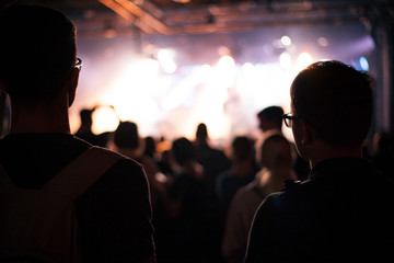 Cheering people crowd in concert show having fun and applause in front of stage lights