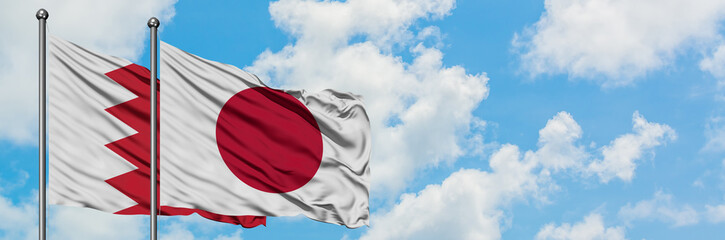 Bahrain and Japan flag waving in the wind against white cloudy blue sky together. Diplomacy concept, international relations.