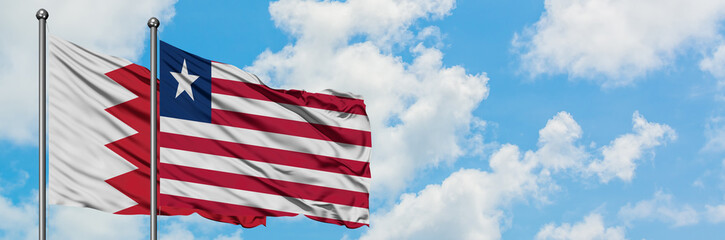 Bahrain and Liberia flag waving in the wind against white cloudy blue sky together. Diplomacy concept, international relations.