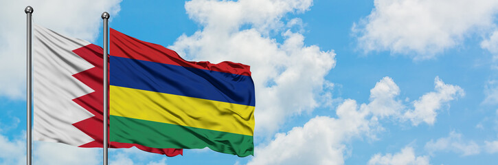 Bahrain and Mauritius flag waving in the wind against white cloudy blue sky together. Diplomacy concept, international relations.