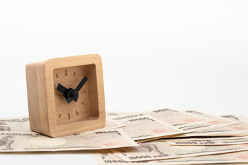 Close up little square wooden clock on japanese currency yen money banknote. Background concept for japan economy and investment.