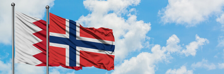 Fototapeta premium Bahrain and Norway flag waving in the wind against white cloudy blue sky together. Diplomacy concept, international relations.