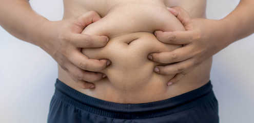 Naklejka premium Overweight Asian obese men, He is feeling ill and worried about his excess weight. He squeezed his belly, showing the excess fat that was isolated on a white background