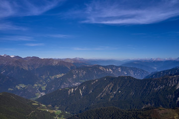 Naklejka na ściany i meble Aerial view of the Alps surrounded by meadows, forests and mountains. Flying on drone.