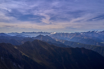 Aerial view of the Alps surrounded by meadows, forests and mountains. Flying on drone.