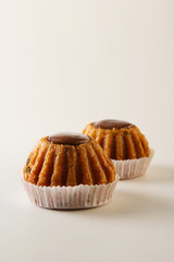 Two freshly baked delicious rum cakes on white background with copy space, selective focus on the foreground, vertical image, low angle