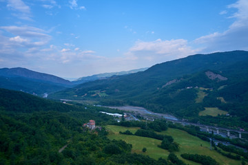 Fototapeta premium Aerial view of the Alps surrounded by meadows, forests and mountains. Flying on drone.
