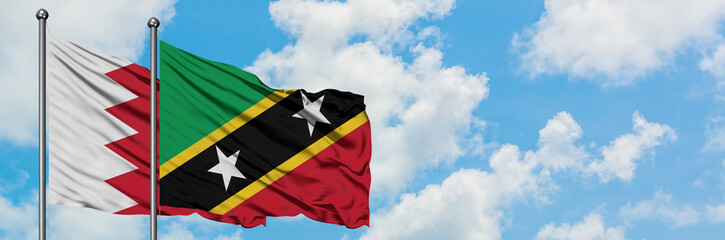 Fototapeta na wymiar Bahrain and Saint Kitts And Nevis flag waving in the wind against white cloudy blue sky together. Diplomacy concept, international relations.