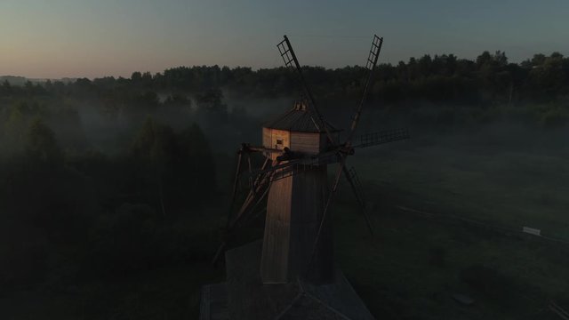 Aerial scenic orange sunrise over old wooden nursery windmill mill natural landscape mystical fog Church silhouette. Museum exhibition Complex New Jerusalem. Beautiful sunset. Sun rays through blades